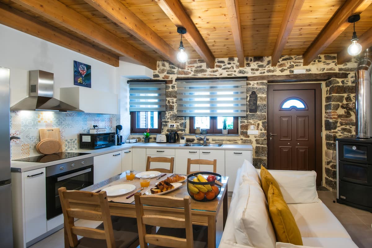 Pièce de vie de Ntoukiani : murs en pierre, poutres en bois et cuisine ouverte