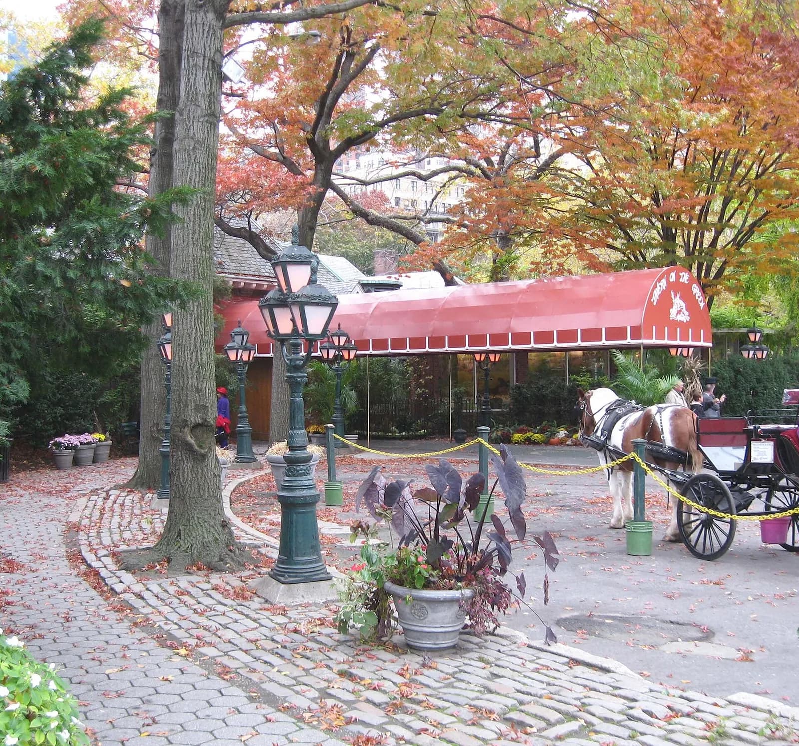 l'entrée du restaurant Tavern on the Green et son auvent rouge sous les arbres d'automne