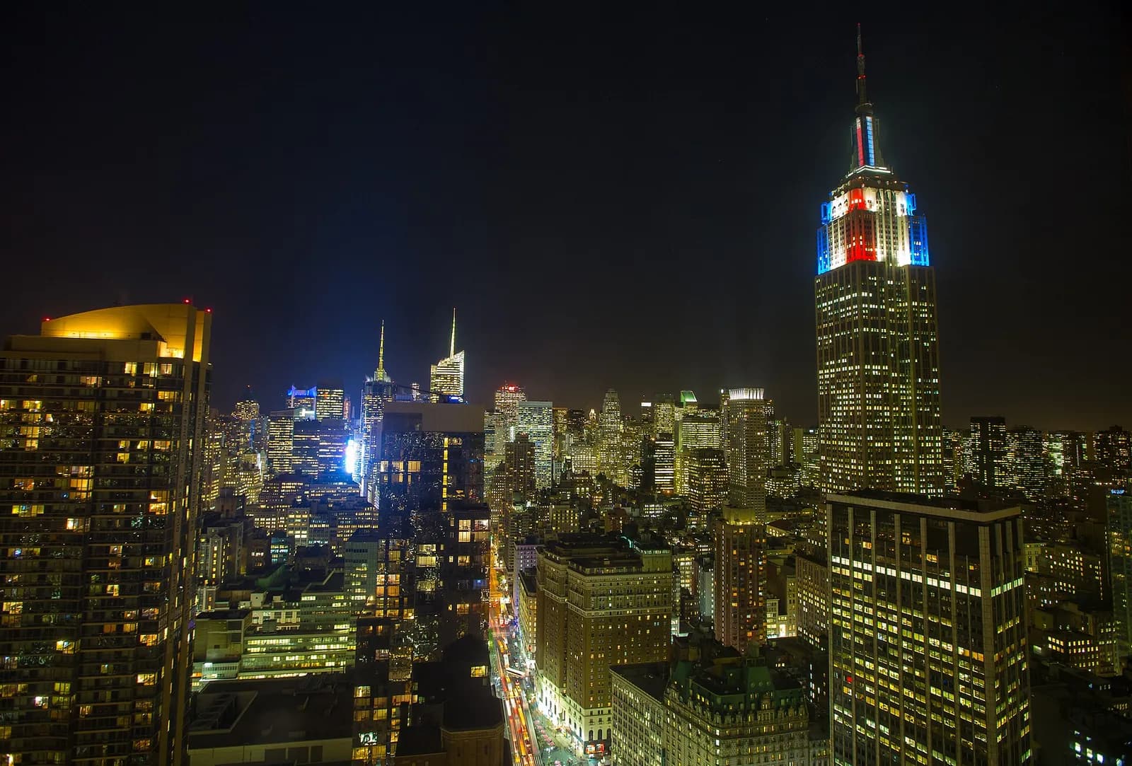 le sommet de l'Empire State Building illuminé en rouge, blanc et bleu la nuit