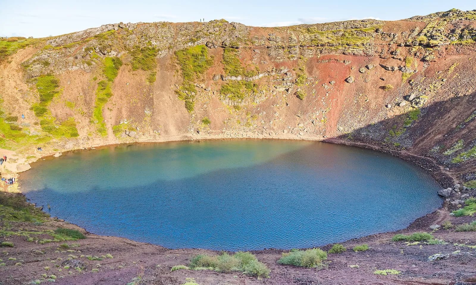le lac bleu du cratère de Kerið au pied des parois ocre couvertes de mousse