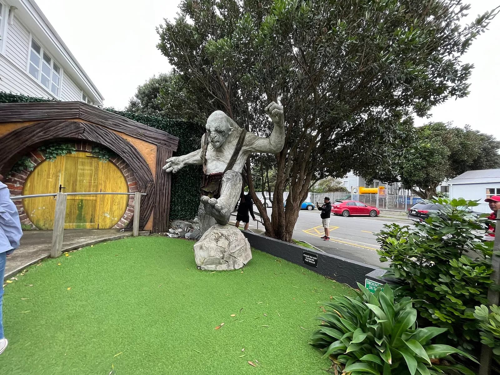 une statue de troll et une porte de hobbit ronde devant la Weta Cave à Wellington