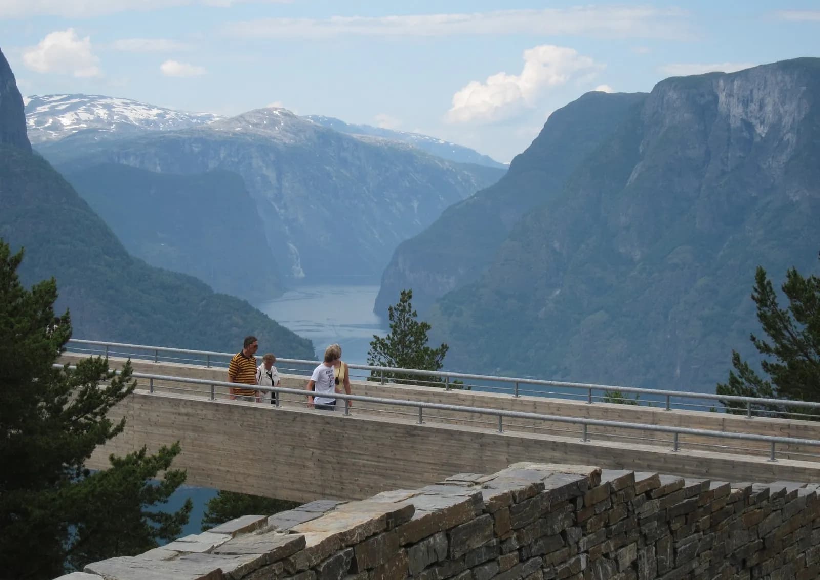 visiteurs accoudés à la rambarde de Stegastein face au fjord et aux sommets enneigés