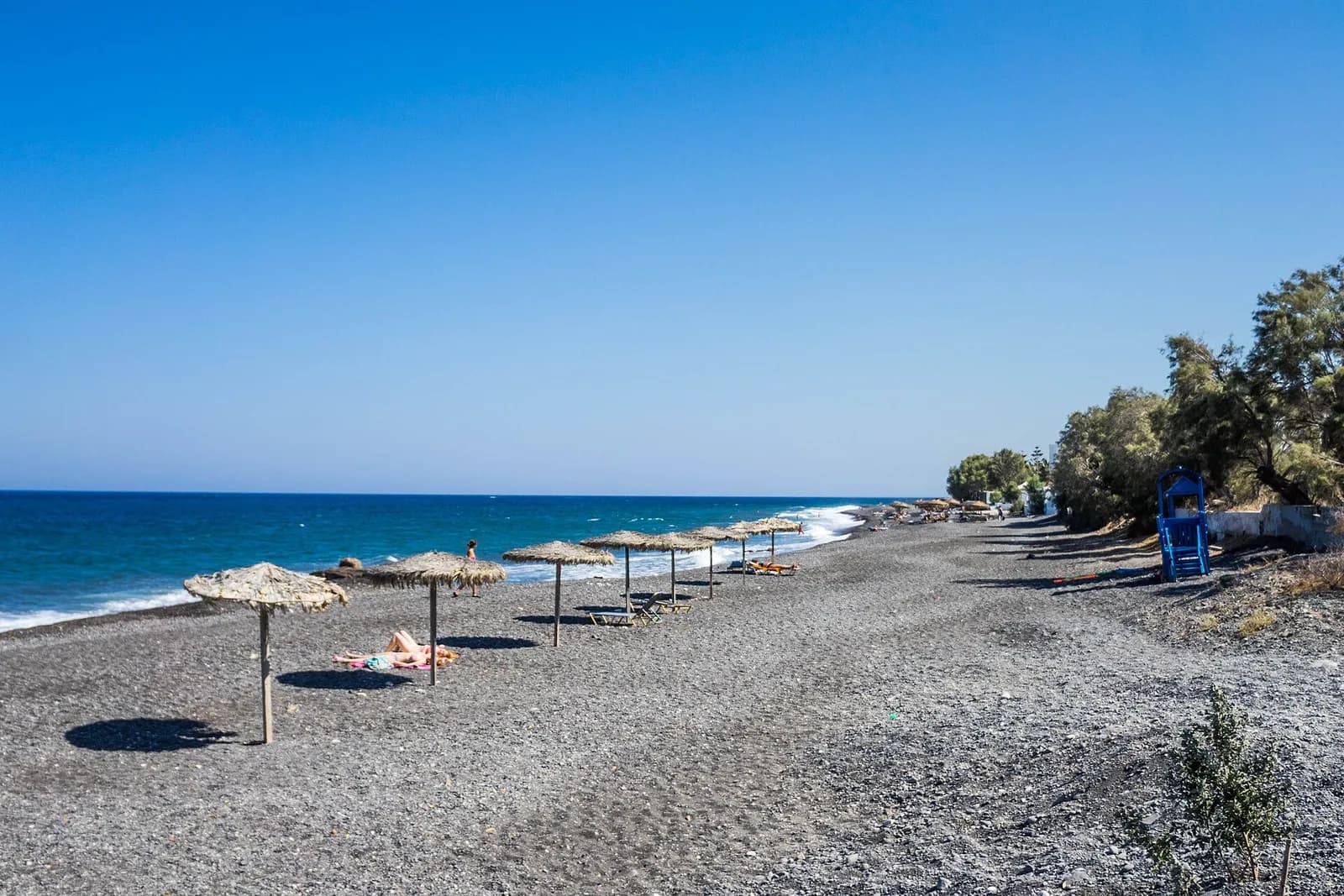 Kamari's black pebble beach with parasols facing the sea