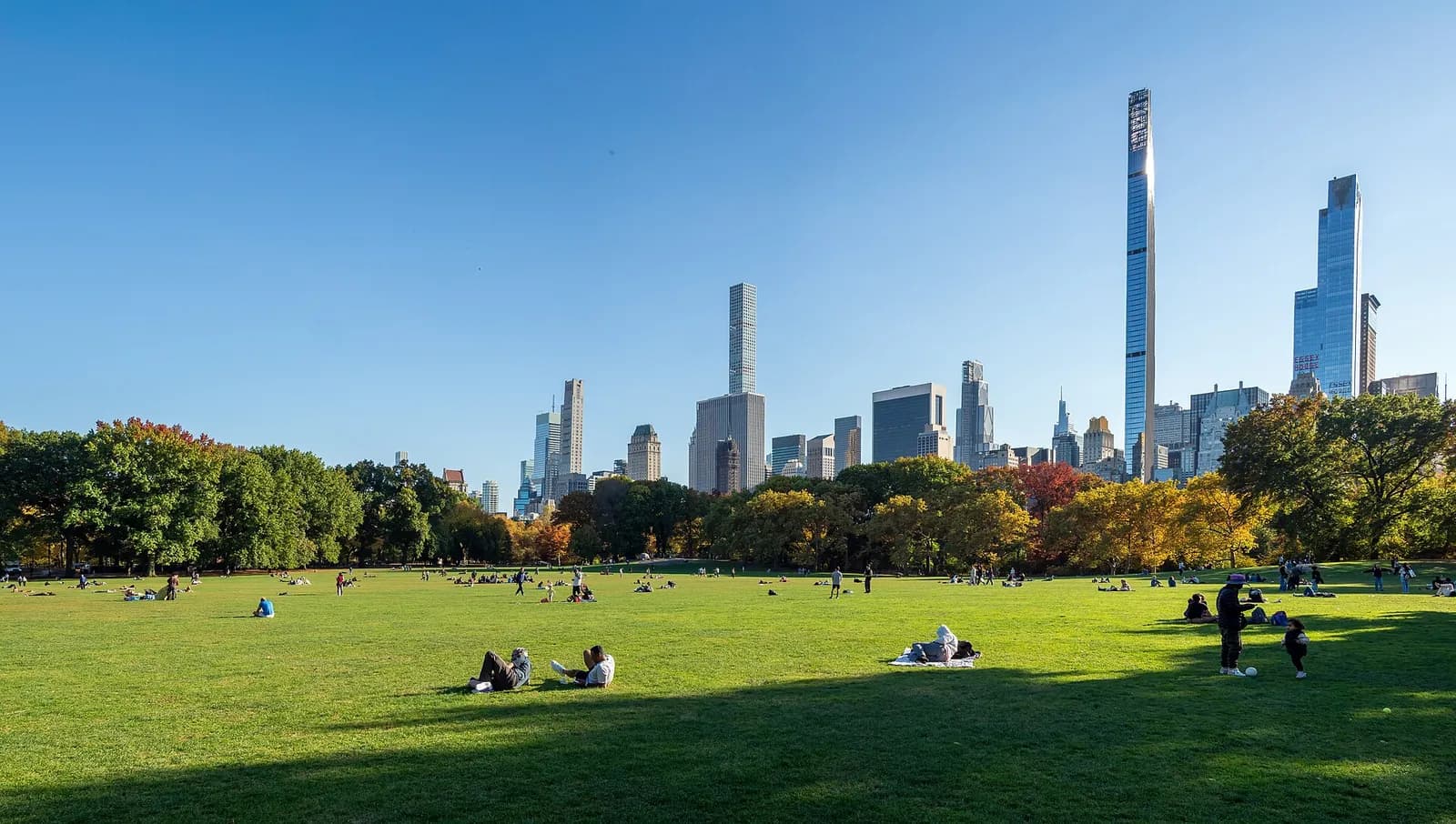 promeneurs allongés sur la pelouse de Sheep Meadow face aux tours de Central Park South
