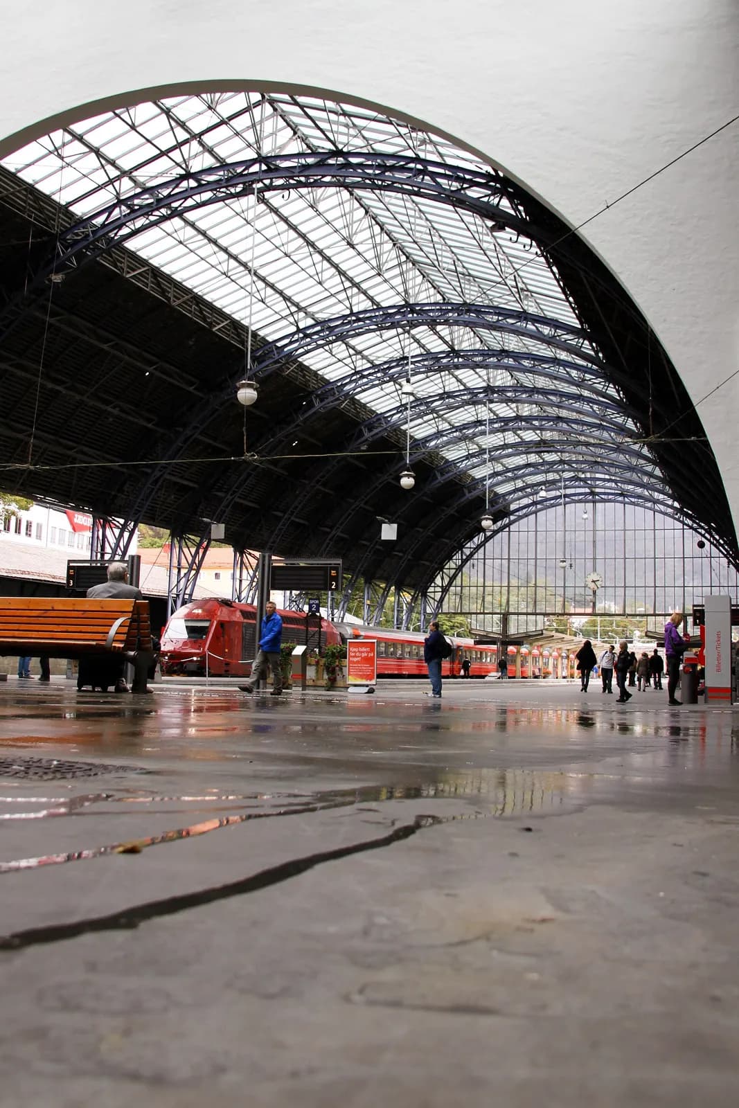 le hall vitré de la gare de Bergen avec des trains rouges à quai