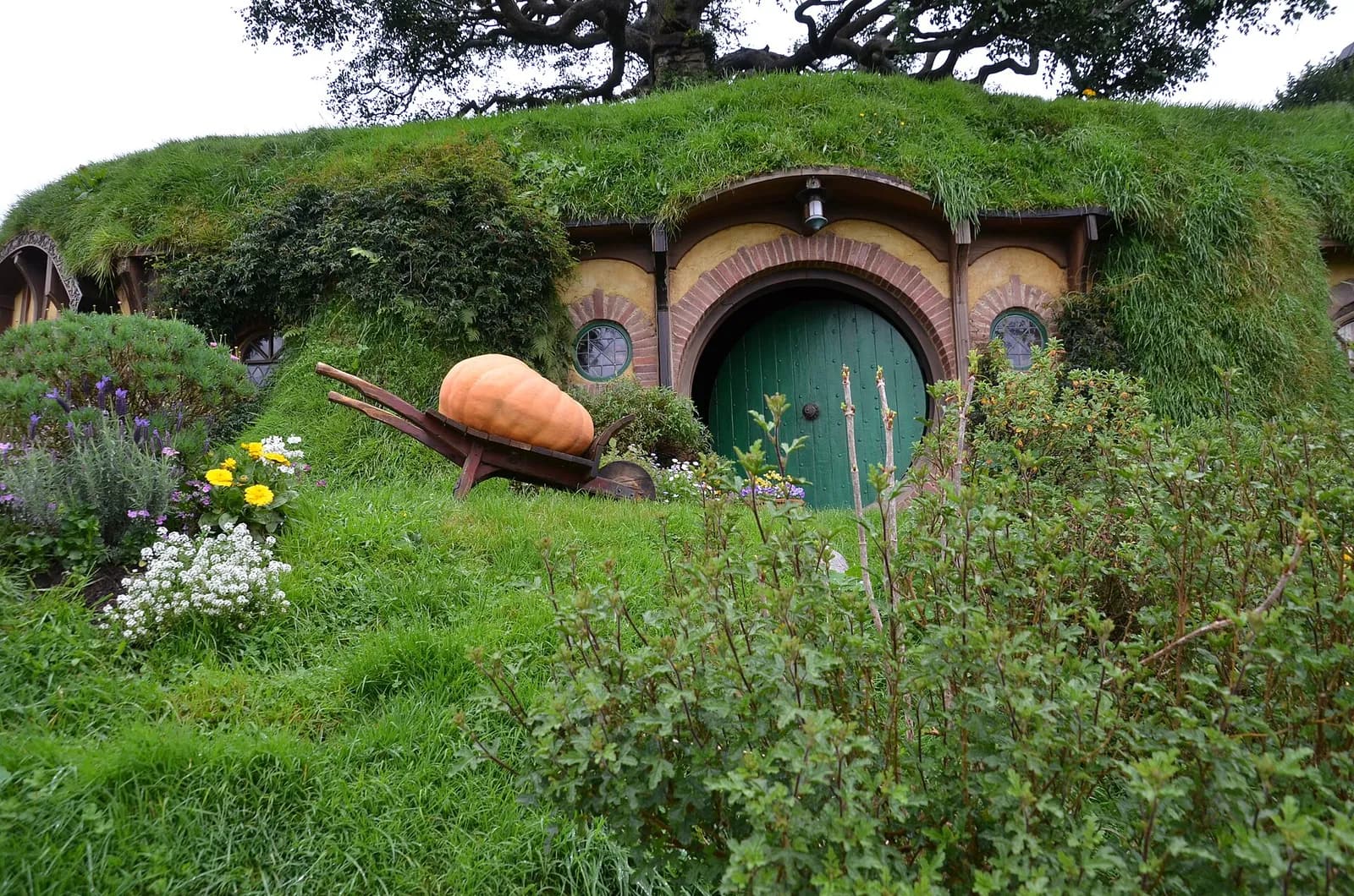 une maison de hobbit à la porte verte et sa brouette de citrouille dans la Comté
