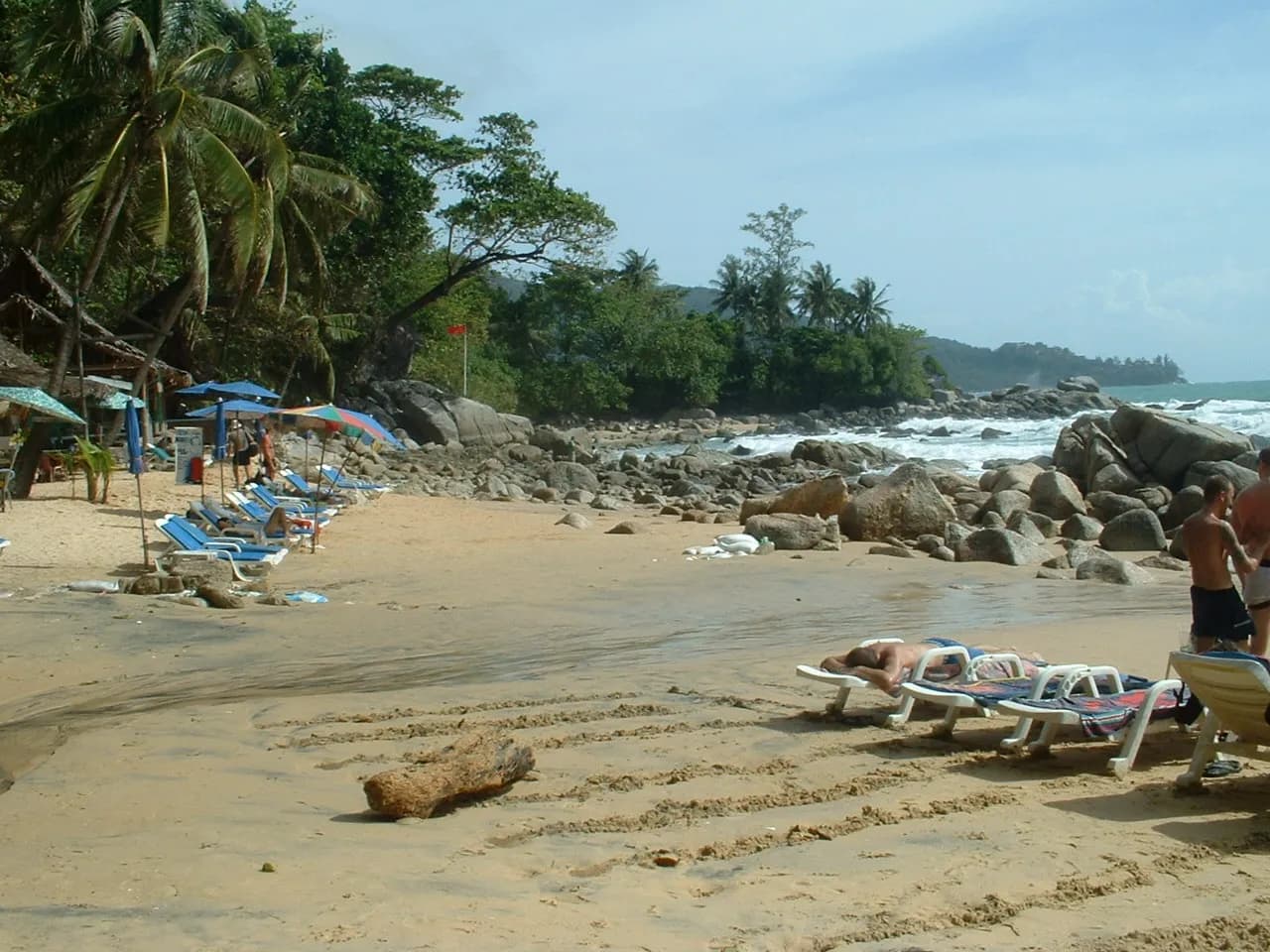 transats sur le sable de Laem Singh Beach entre palmiers et gros rochers