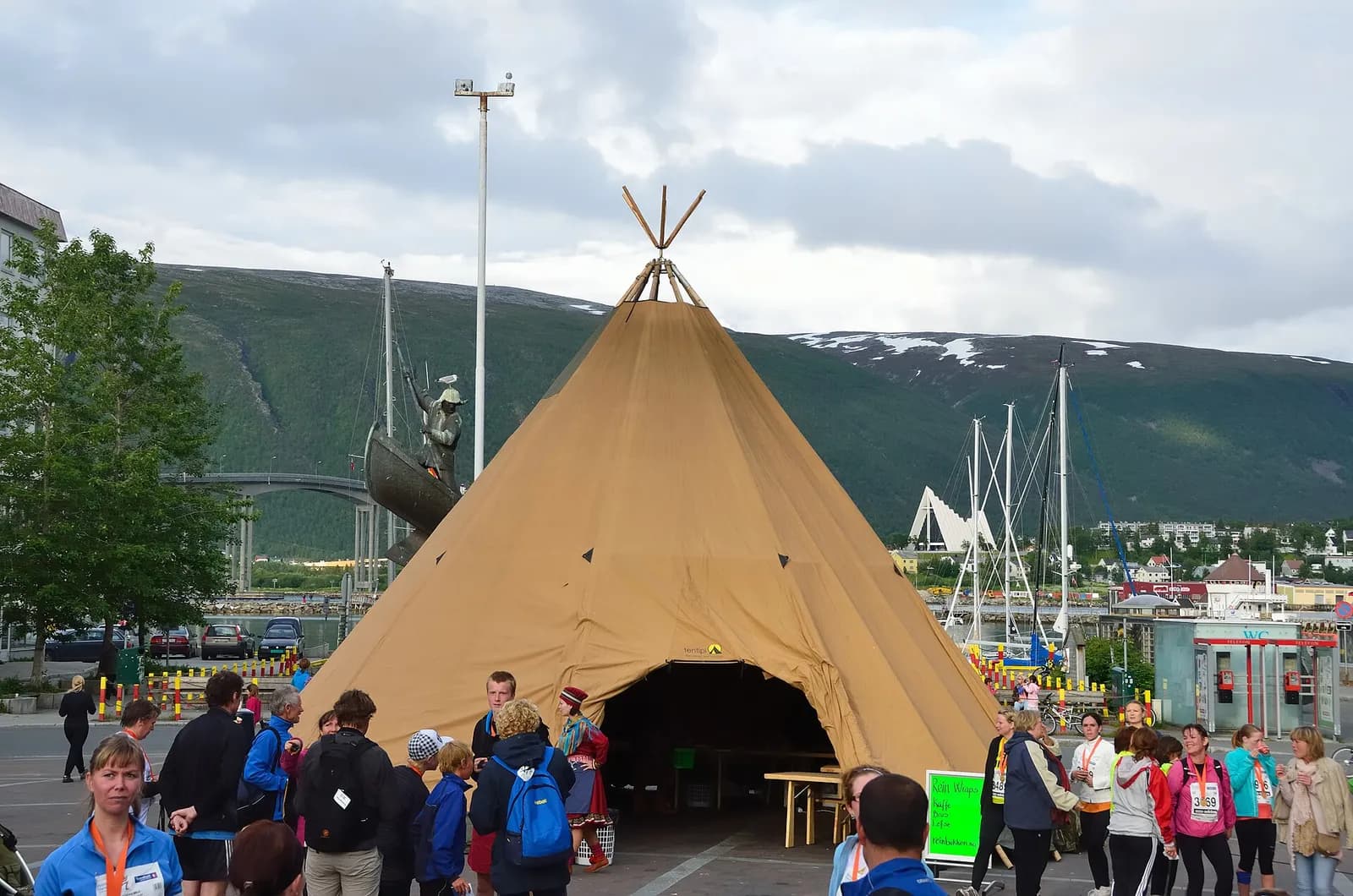 grand lavvu sami dressé sur le port de Tromsø, avec la cathédrale arctique au loin