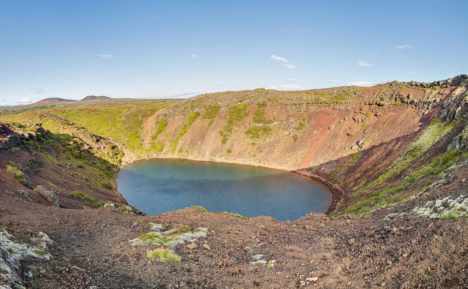 le cratère volcanique de Kerið et son lac bleu entouré de parois rouges et vertes