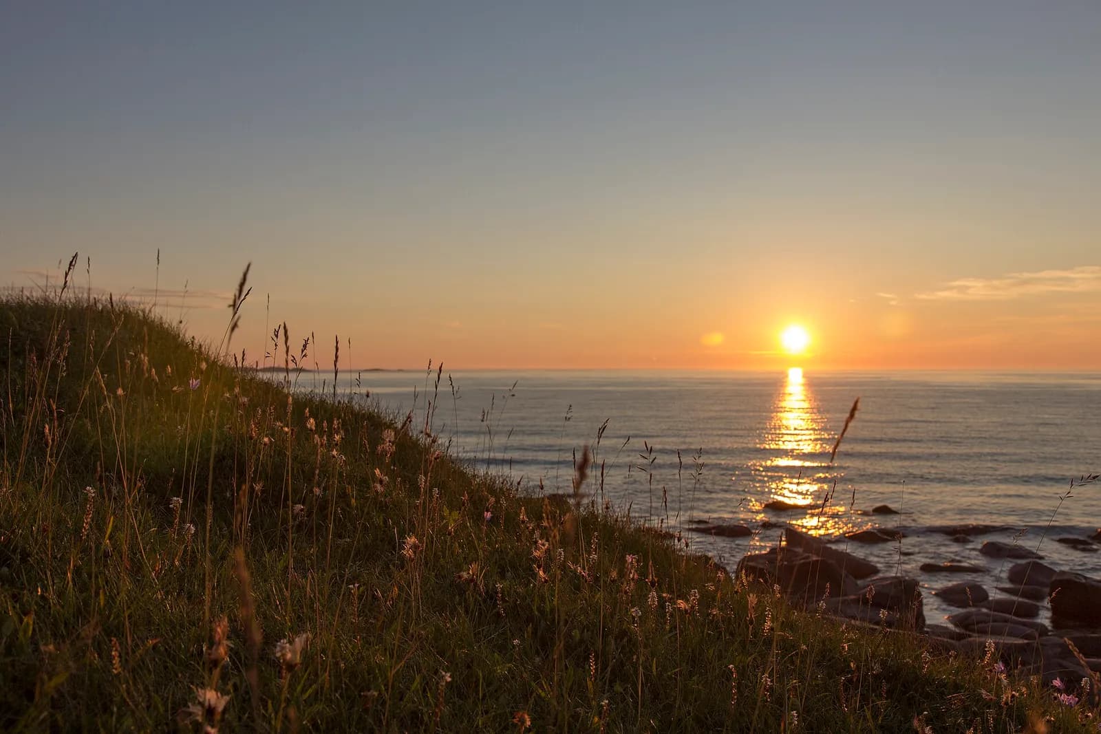 le soleil de minuit posé sur l'horizon et se reflétant dans la mer aux Lofoten