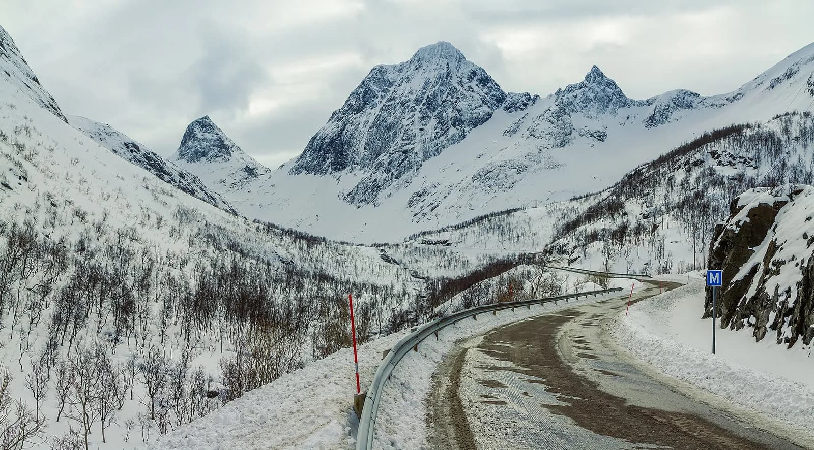 la route de Bergsfjord serpente sous des sommets enneigés sur l'île de Senja en hiver