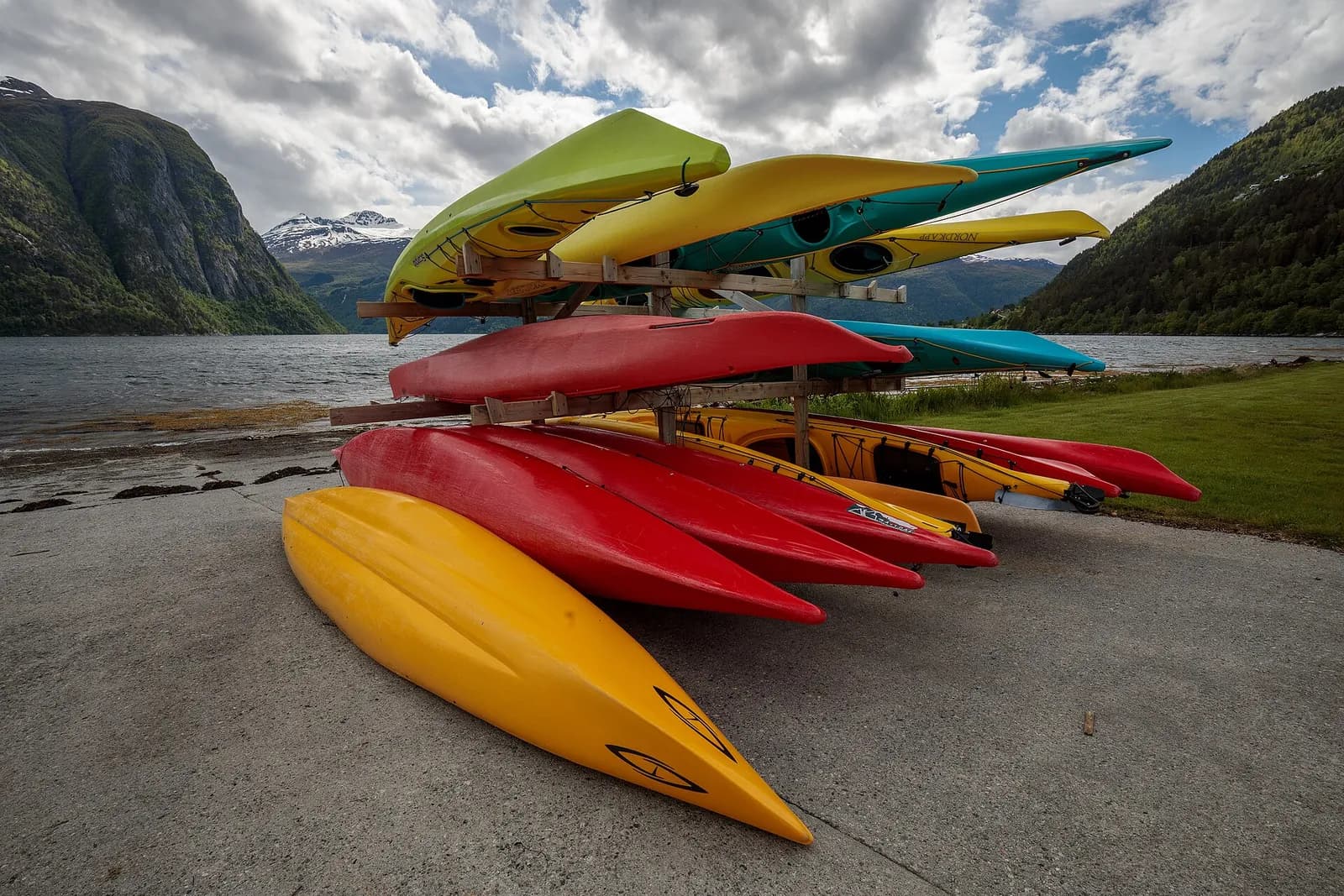 kayaks colorés empilés sur un râtelier au bord d'un fjord norvégien