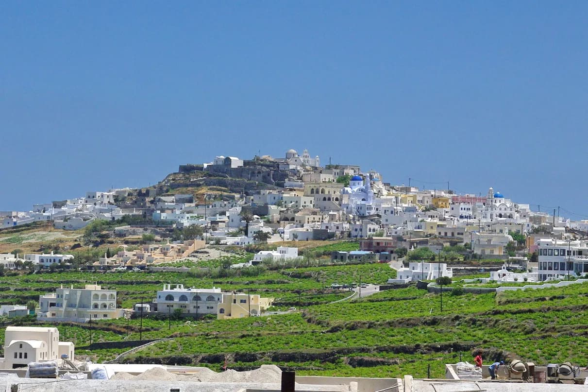 le village perché de Pyrgos dominant les vignobles de Santorin sous un ciel bleu