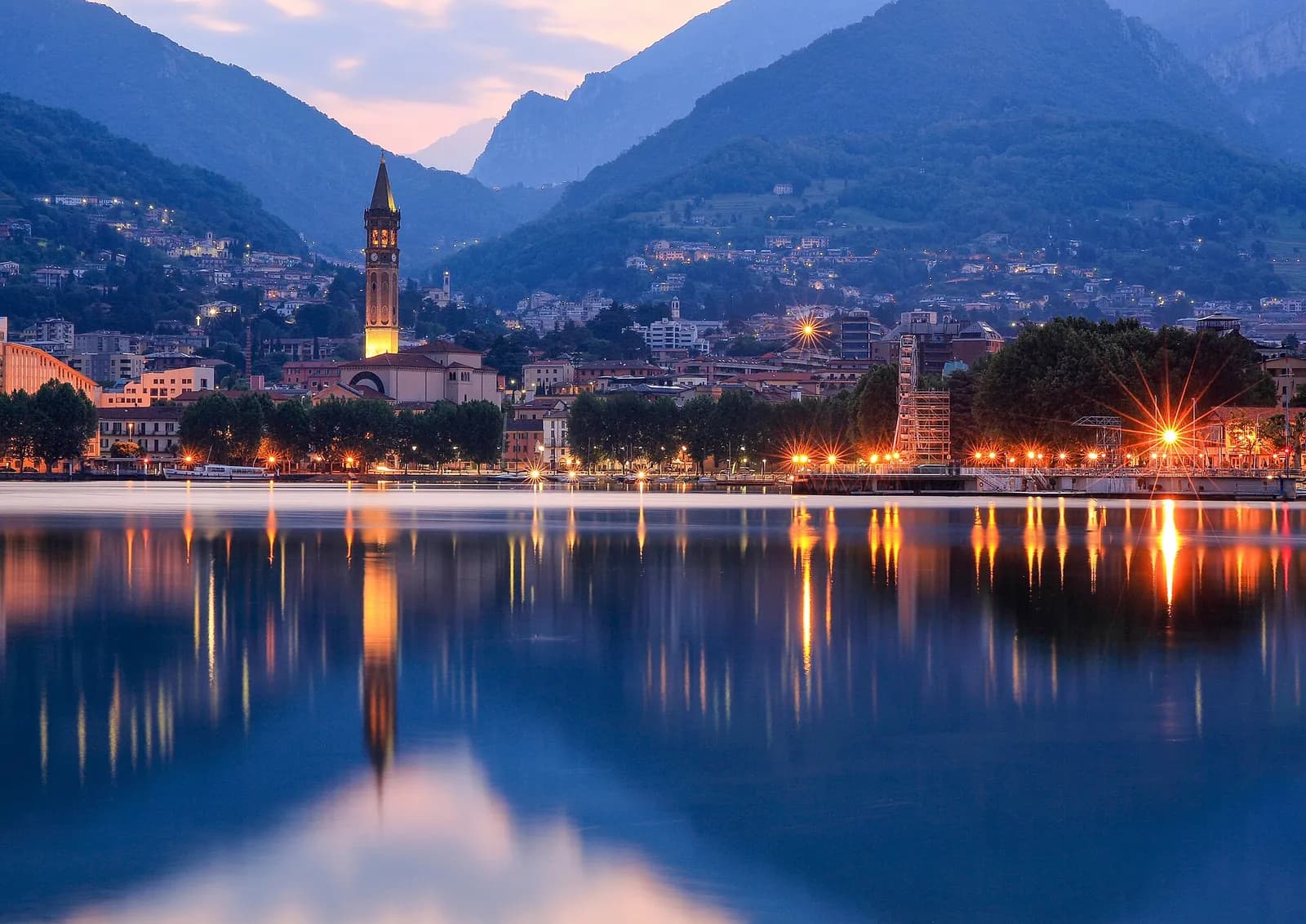 les lumières de Lecco et son campanile se reflétant dans le lac à la tombée du jour