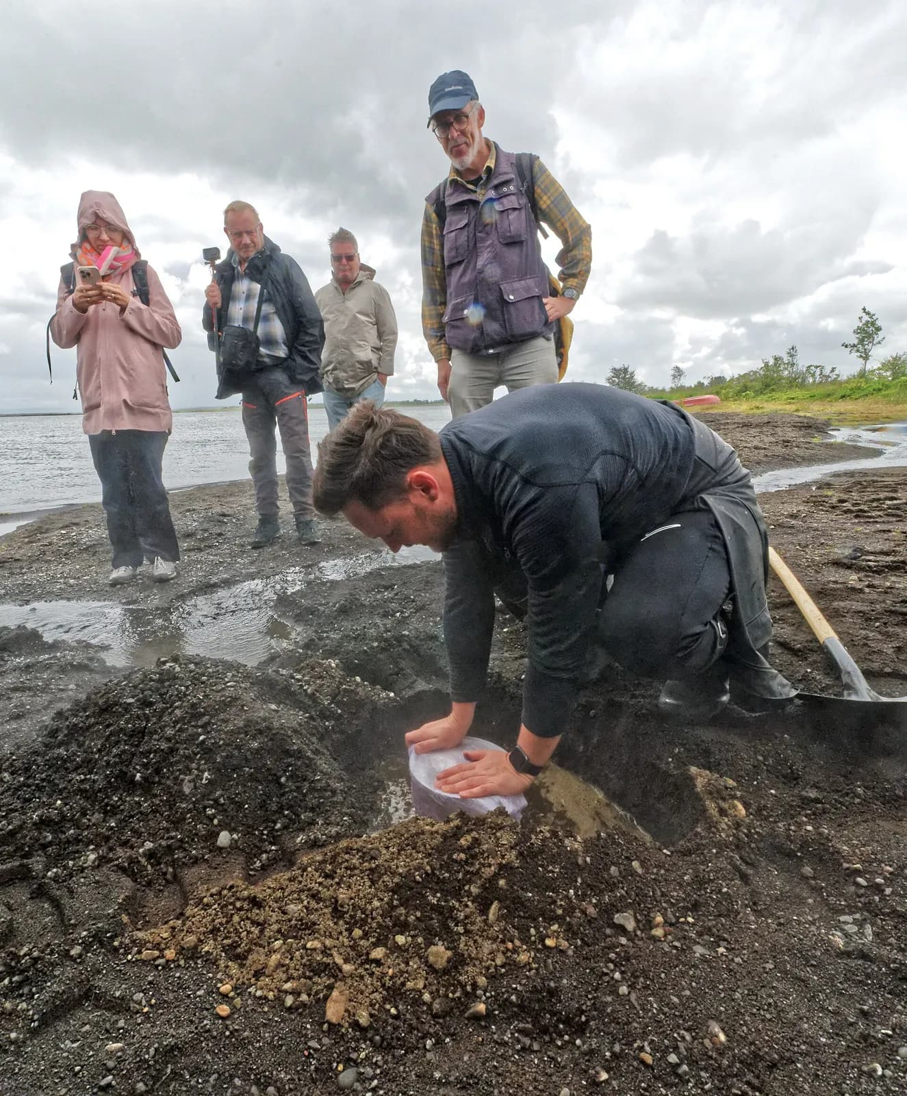 un boulanger enterre la marmite de pain dans le sable brûlant au bord du lac Laugarvatn