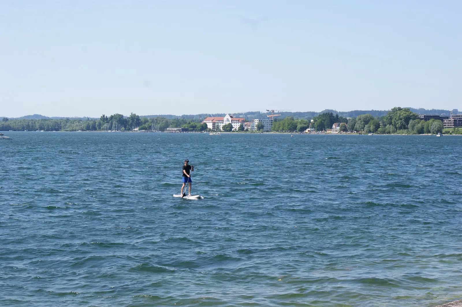 paddleur solitaire sur les eaux bleues d'un grand lac alpin par temps clair