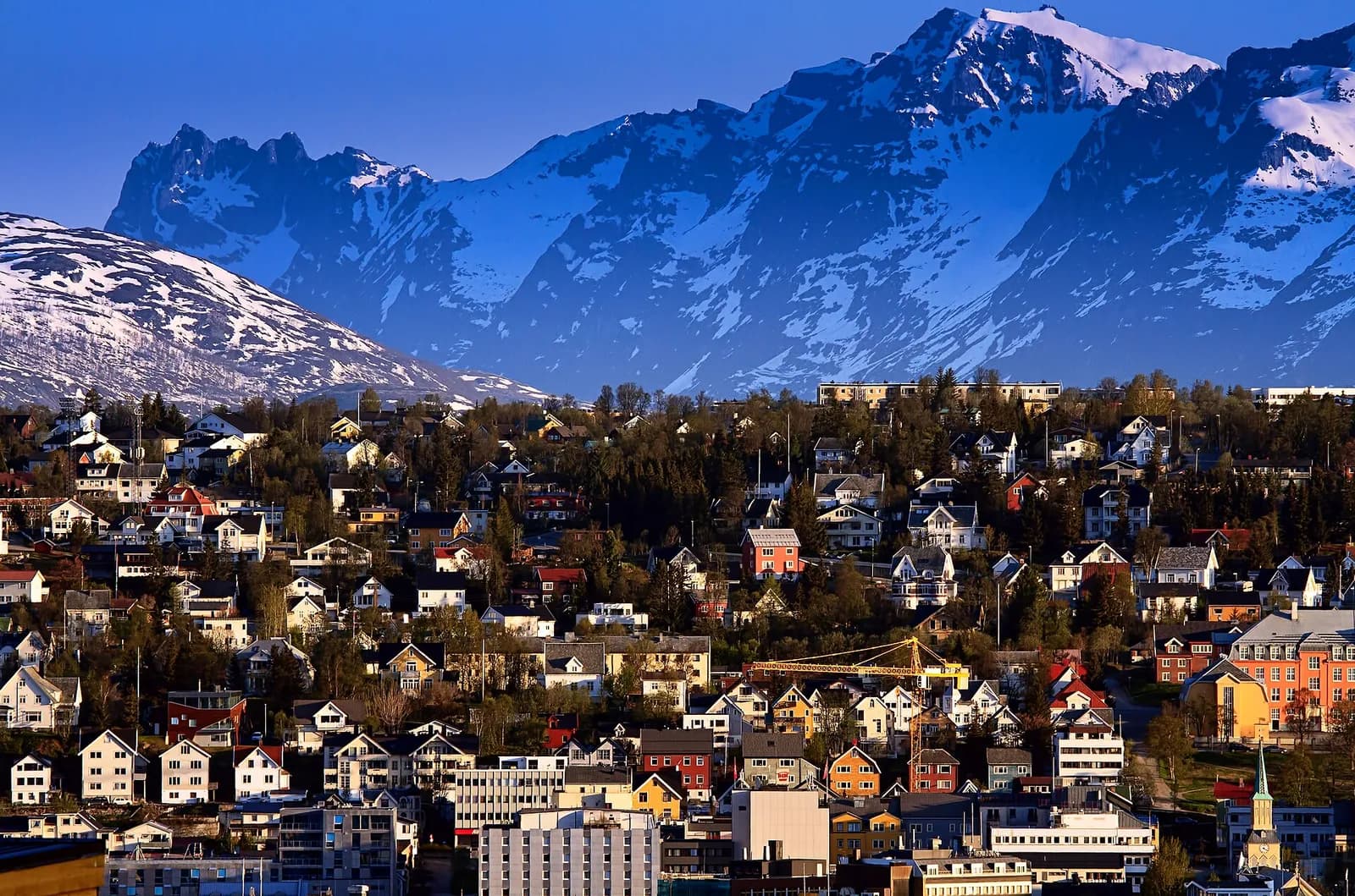 maisons colorées de Tromsø au pied de montagnes enneigées sous un ciel bleu