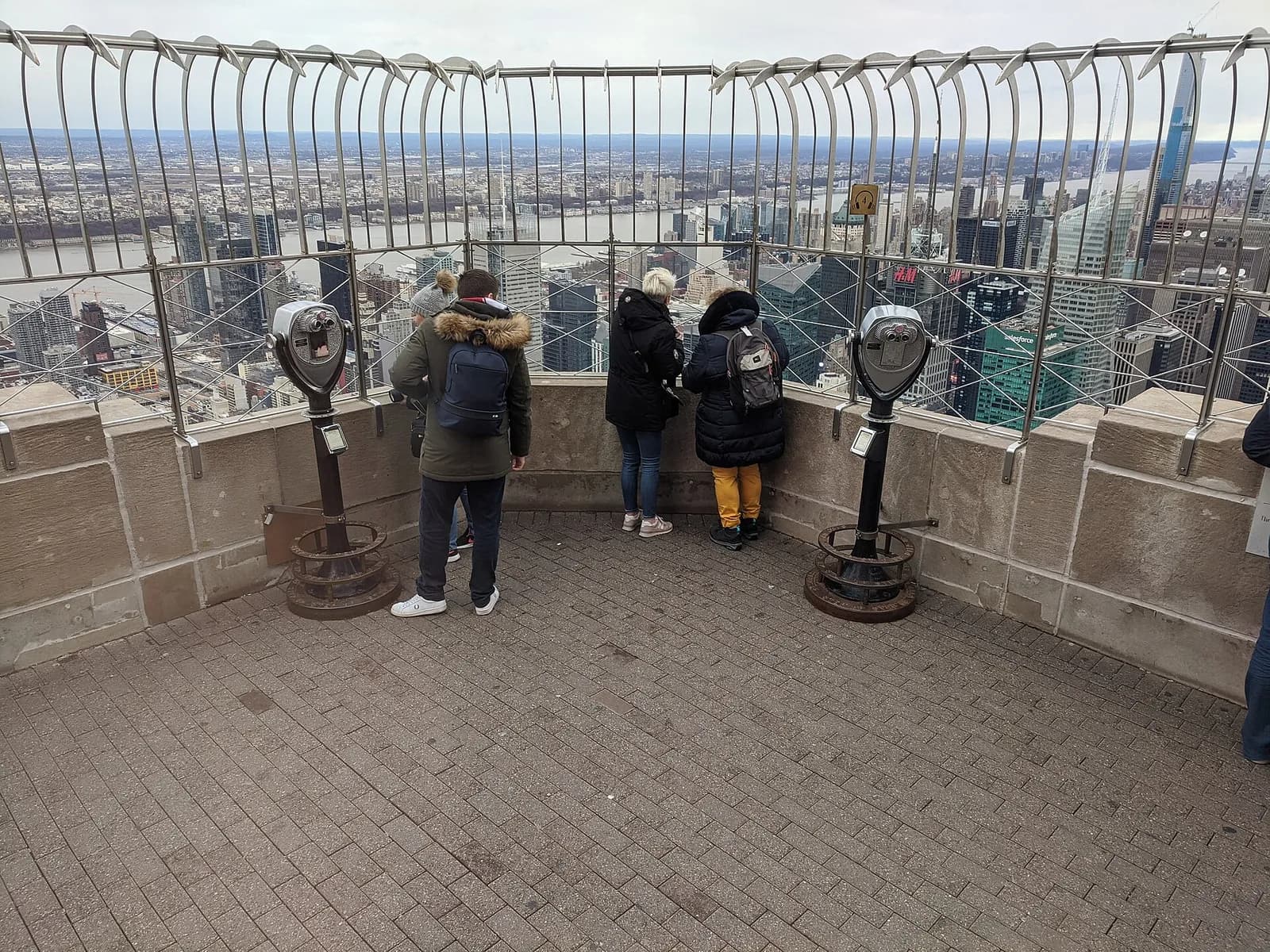 visiteurs sur la terrasse du 86e étage, derrière la grille, face aux gratte-ciels de Manhattan