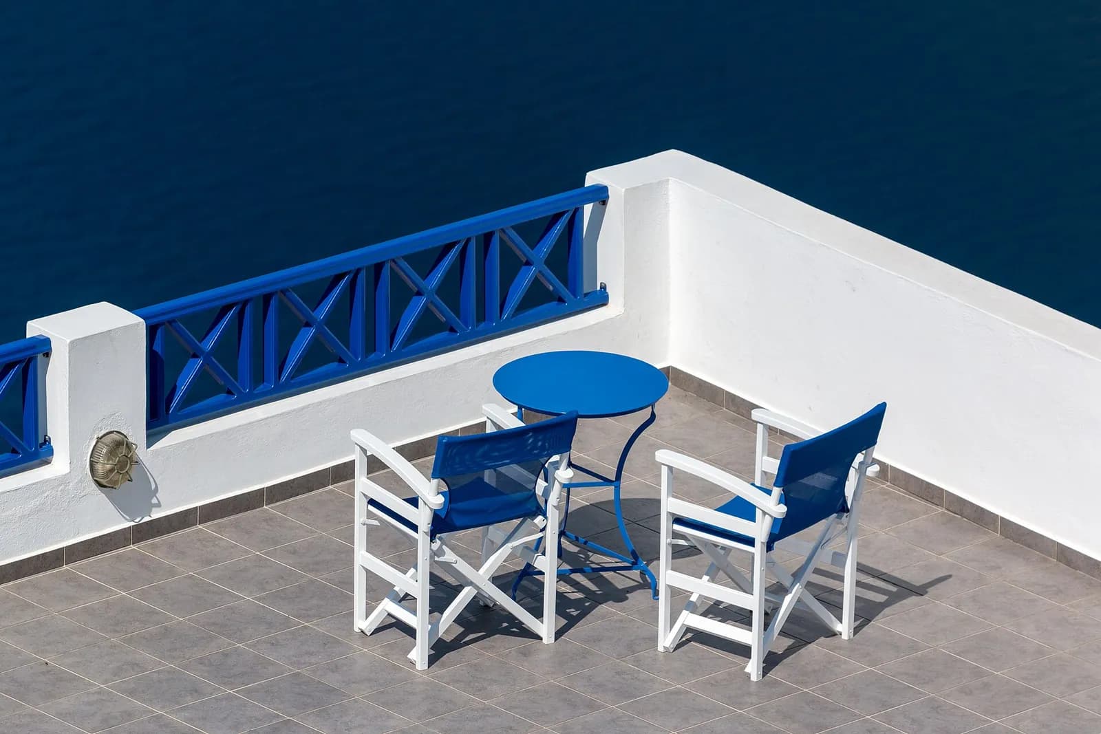 a blue table and chairs on a Fira terrace overlooking the sea