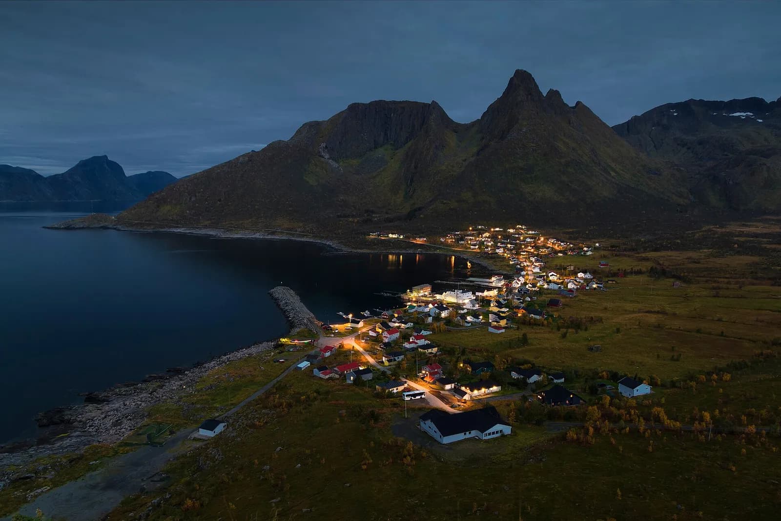les lumières du village de Mefjordvær brillent au crépuscule entre fjord et montagnes