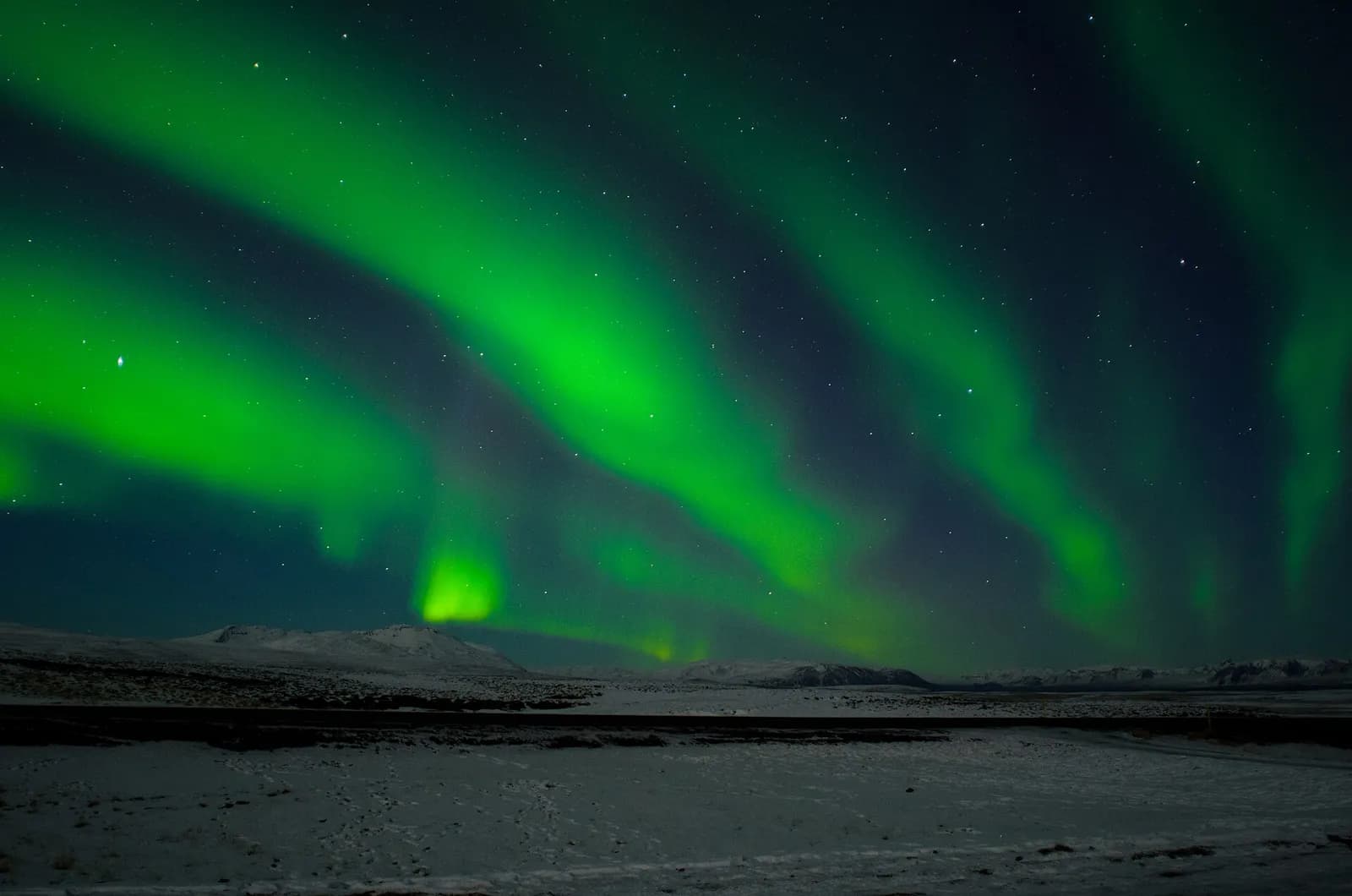 aurores boréales vertes dansant au-dessus d'une plaine enneigée dans le sud de l'Islande