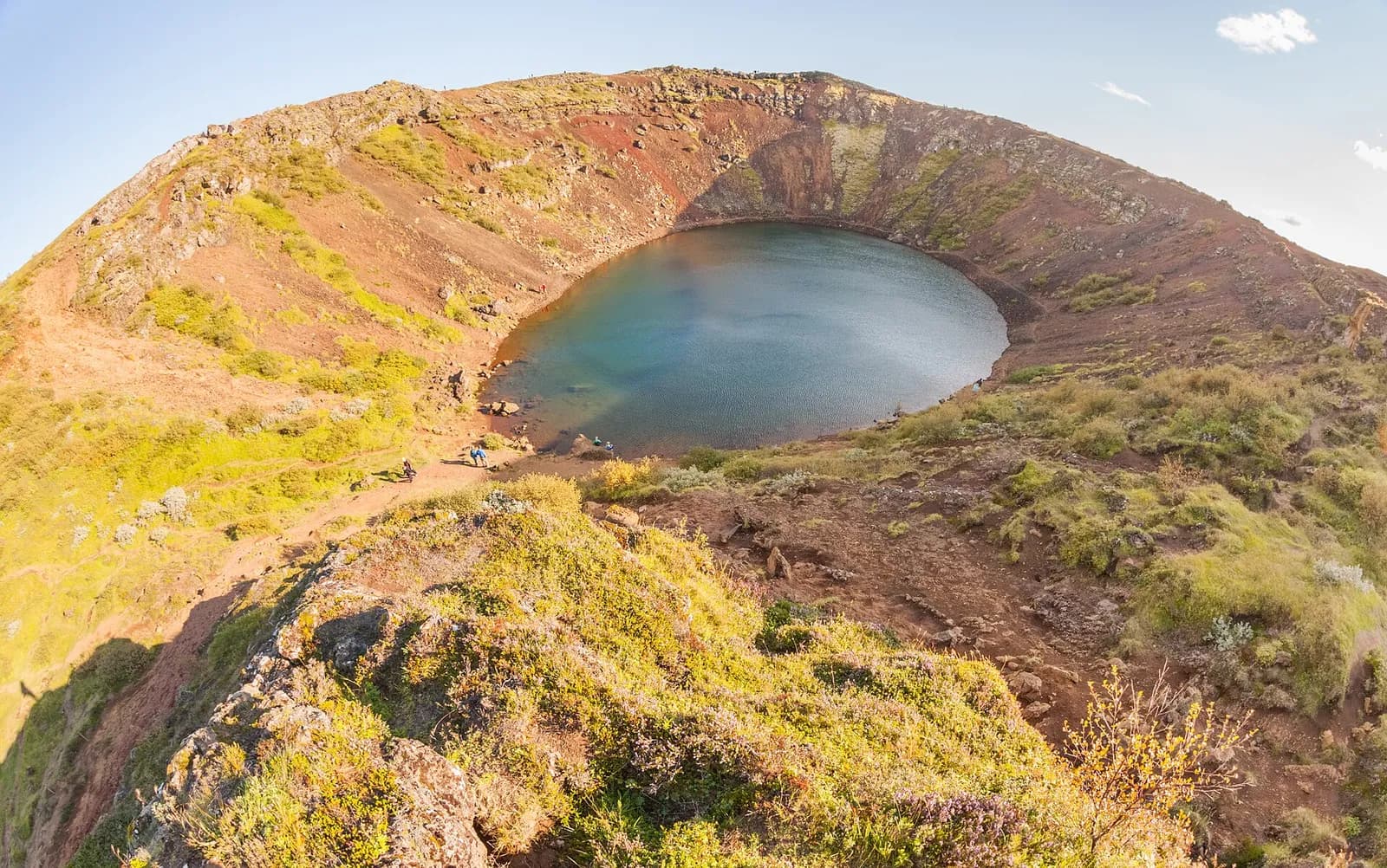 le cratère de Kerið baigné de lumière dorée, lac bleu au centre des pentes moussues