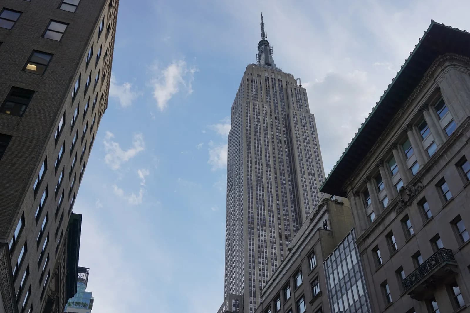 la tour de l'Empire State Building vue depuis le trottoir, entre deux immeubles