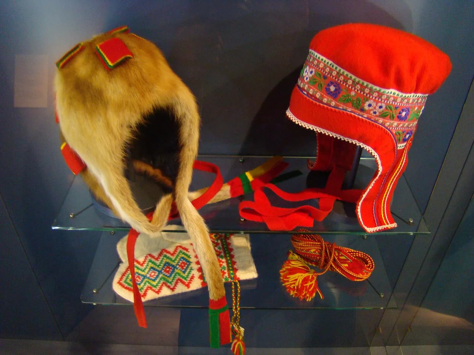 bonnets traditionnels sami en fourrure et en tissu brodé exposés en vitrine