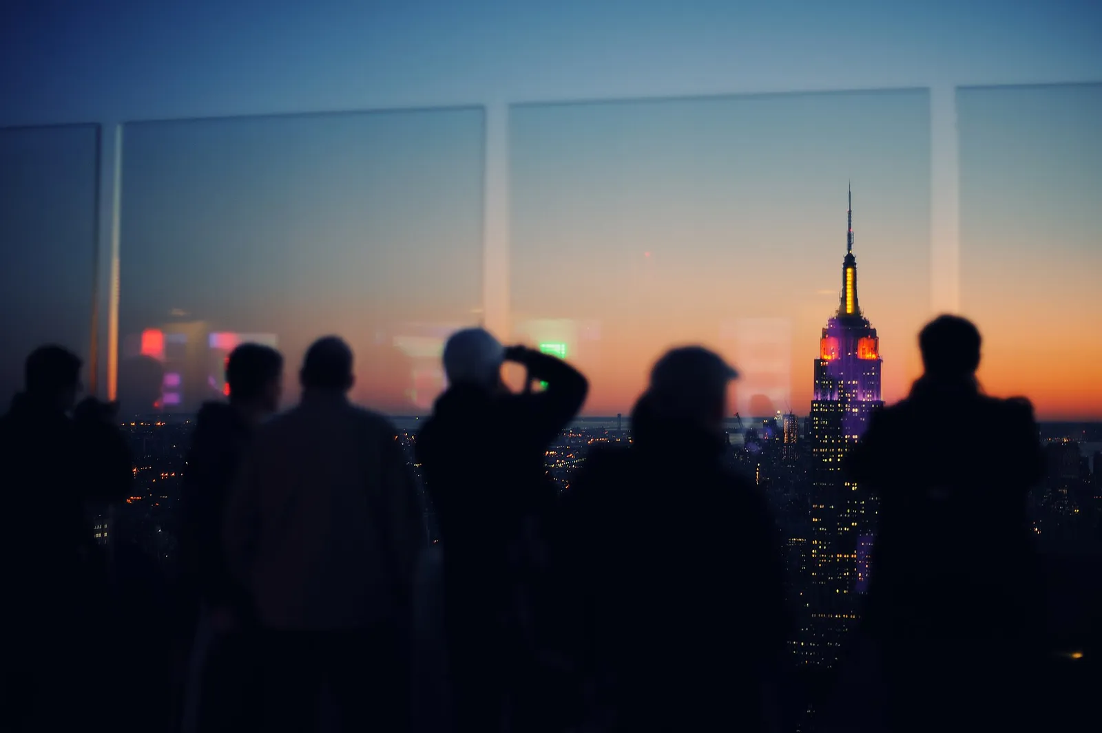 silhouettes de visiteurs admirant l'Empire State Building illuminé au crépuscule