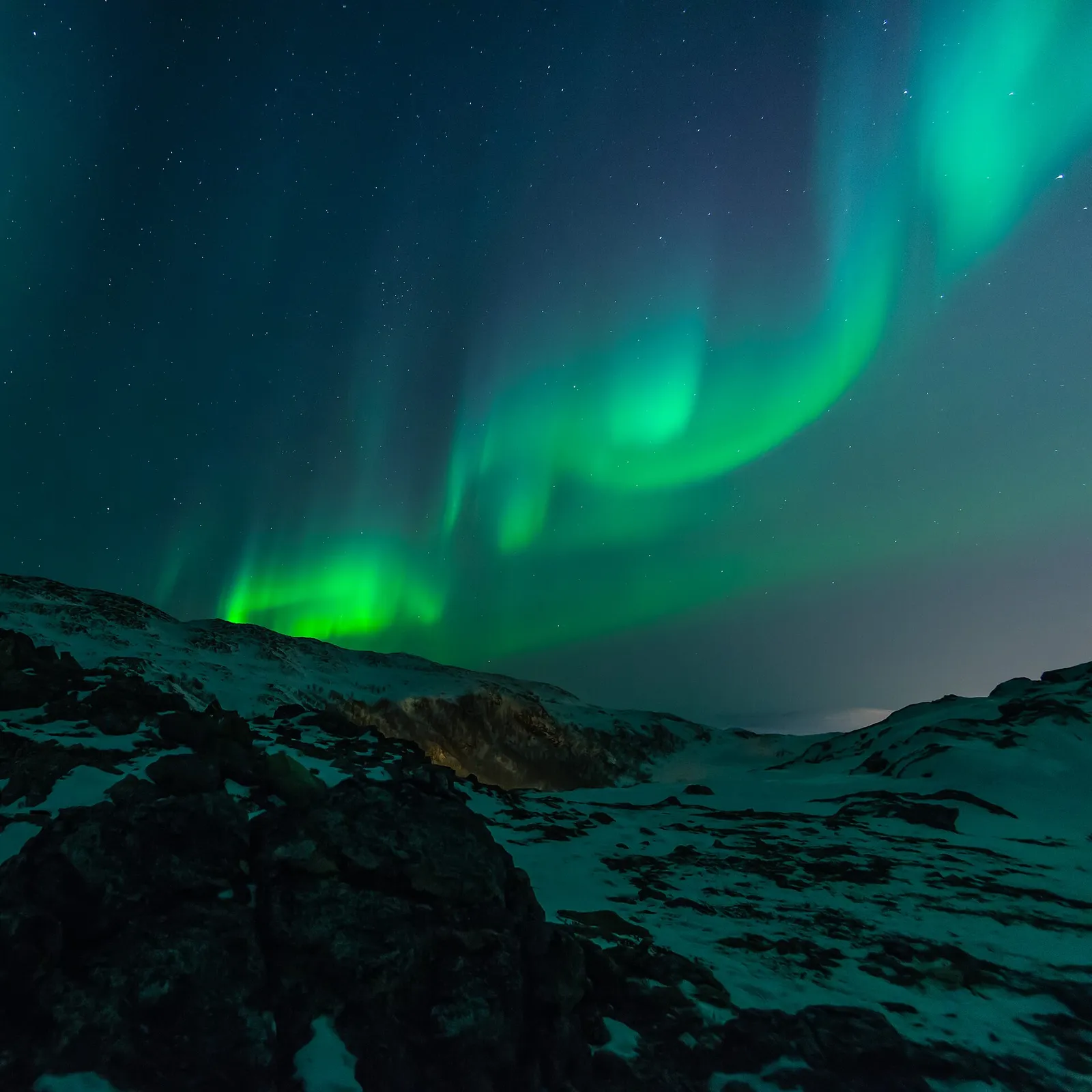 aurore boréale verte au-dessus d'un paysage rocheux enneigé dans le nord de la Norvège