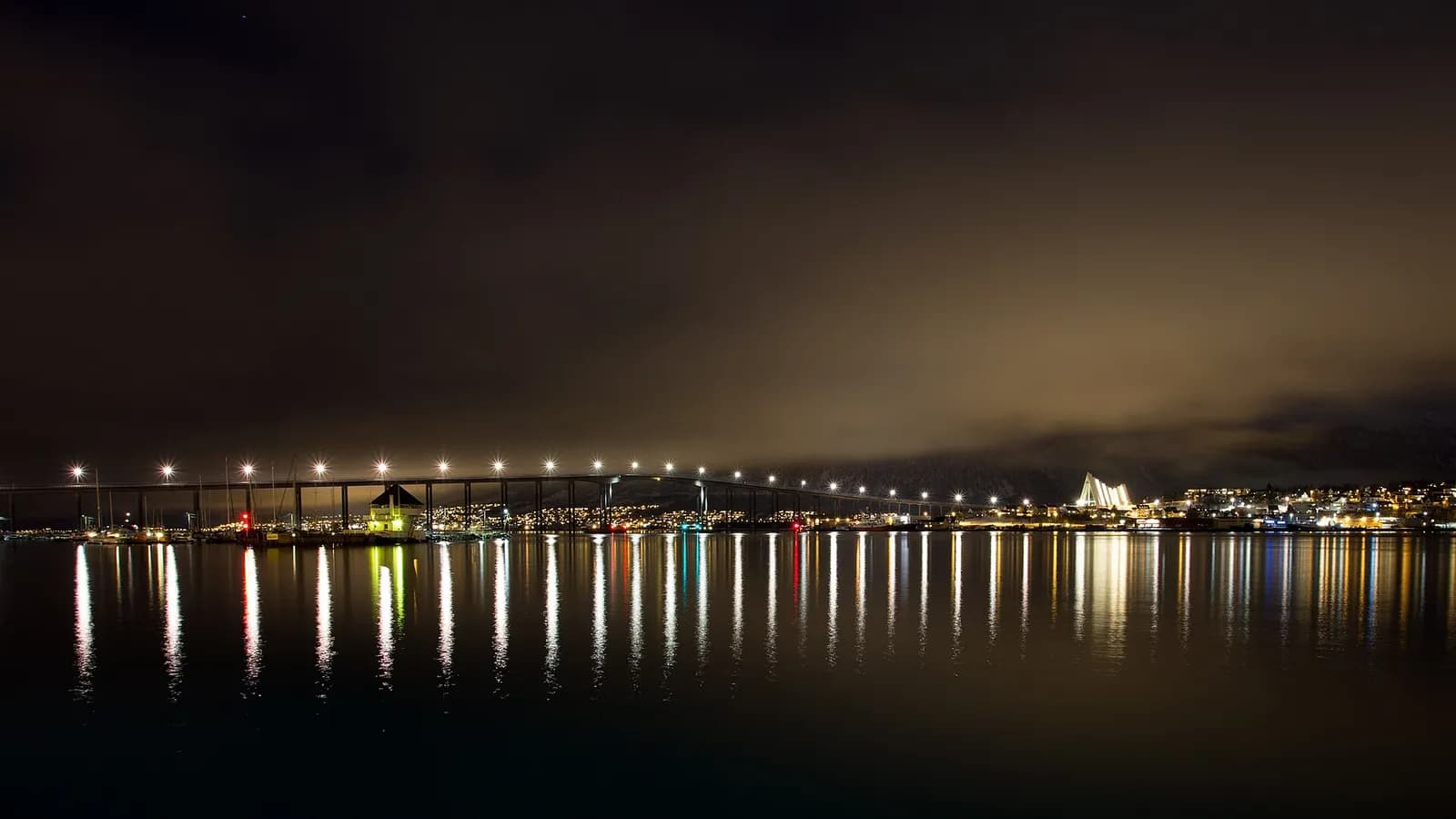 le pont de Tromsø et la cathédrale arctique illuminés se reflétant dans le détroit la nuit