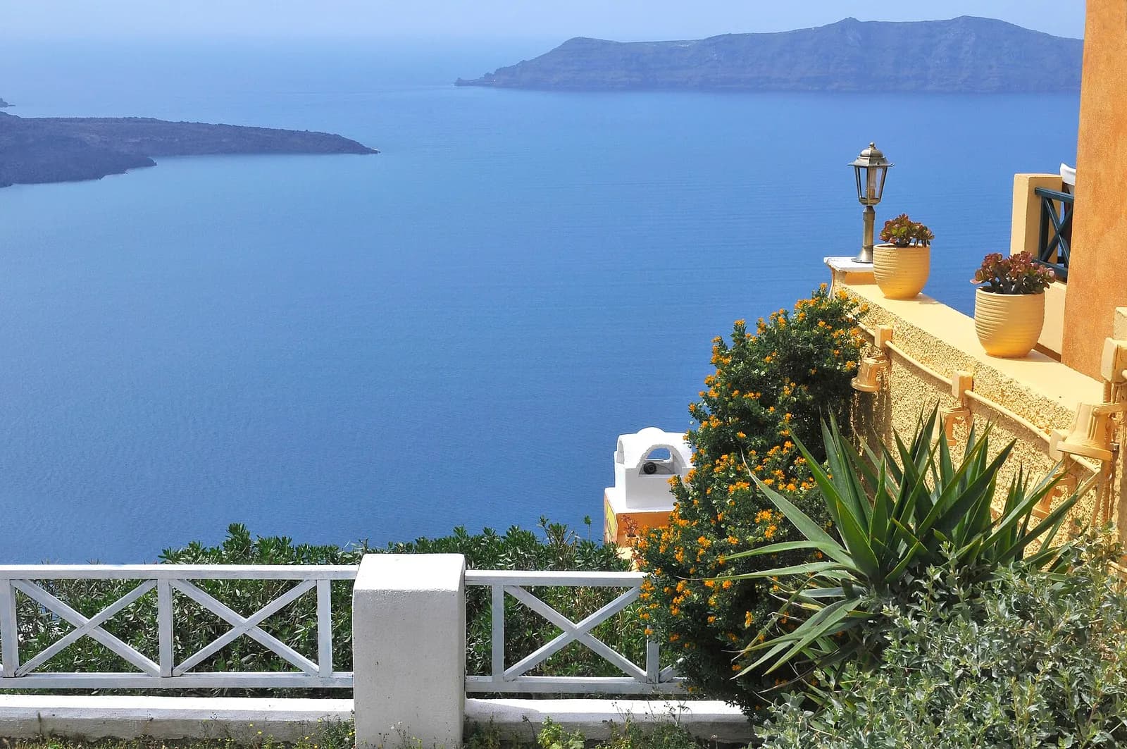 a flower-filled terrace in Firostefani looking out over the caldera and Nea Kameni