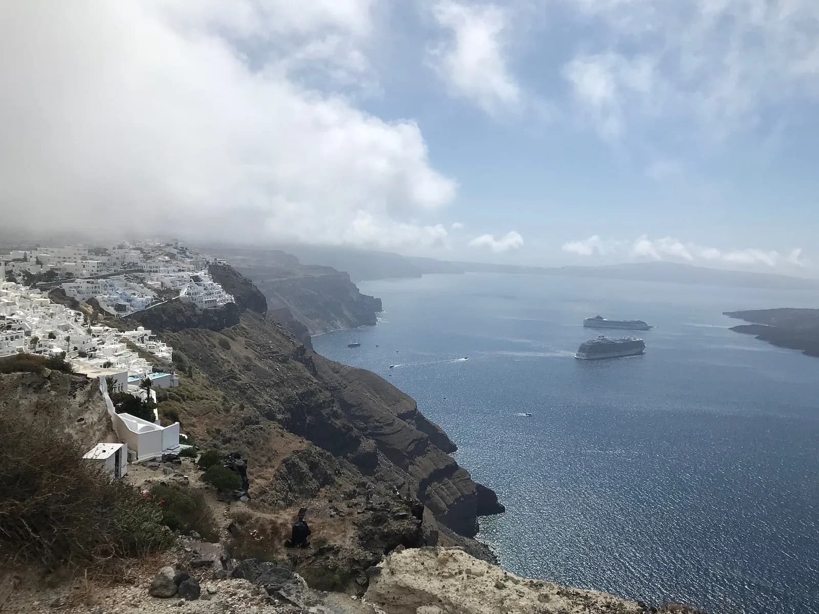 view of Firostefani and Fira perched above the caldera under a cloudy sky