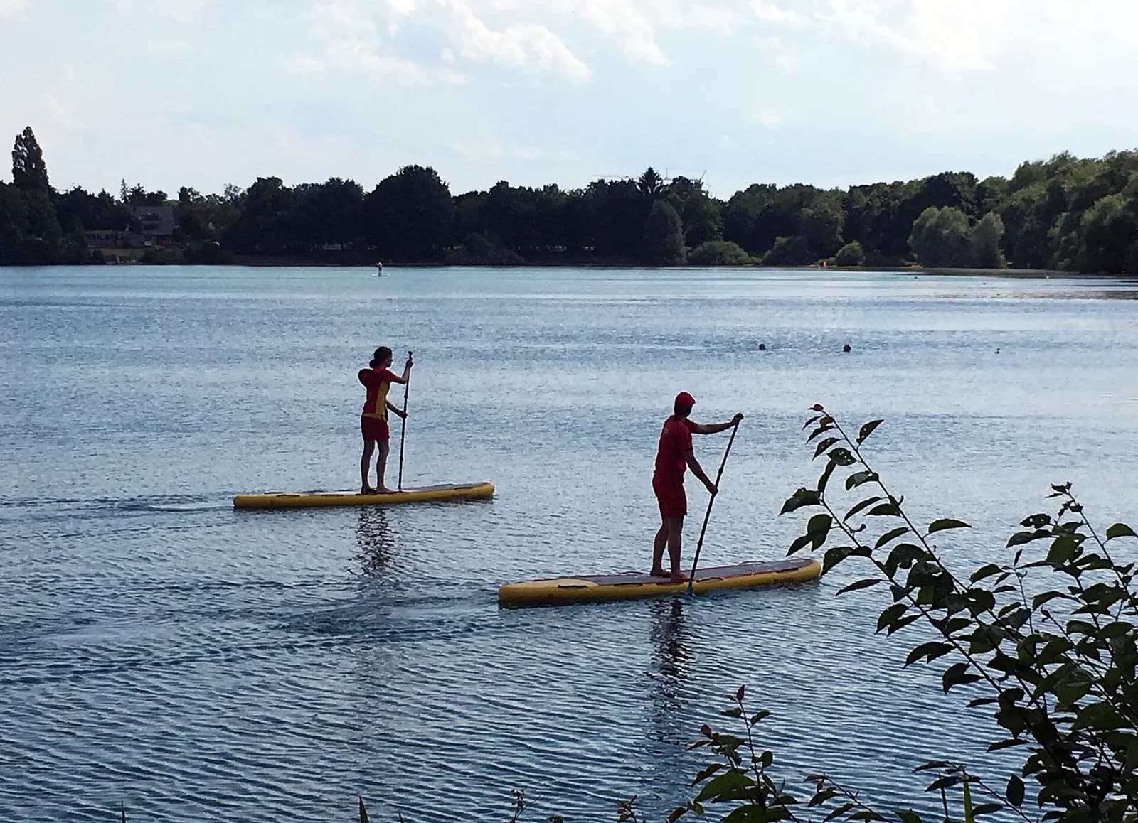 deux sauveteurs sur des planches de paddle surveillant une zone de baignade d'un lac