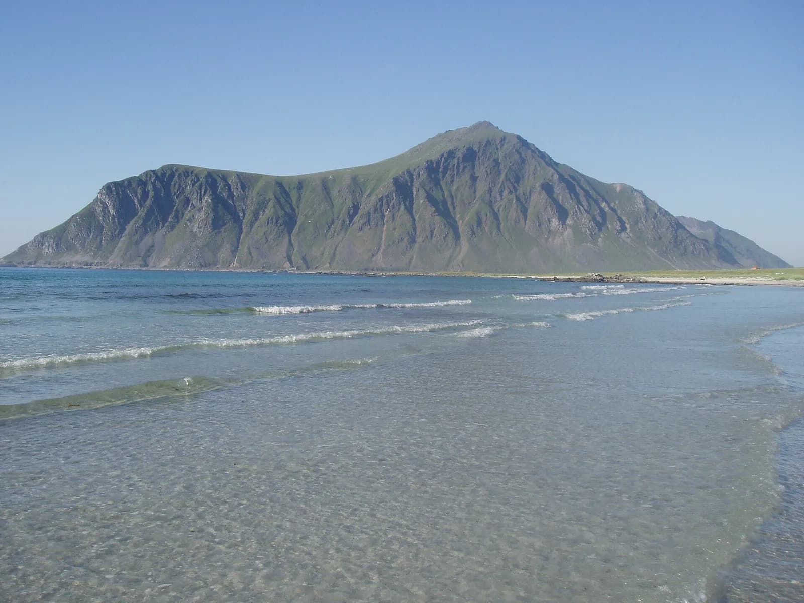 les vagues douces de la plage de Skagsanden face à la montagne Hustinden, à Flakstad