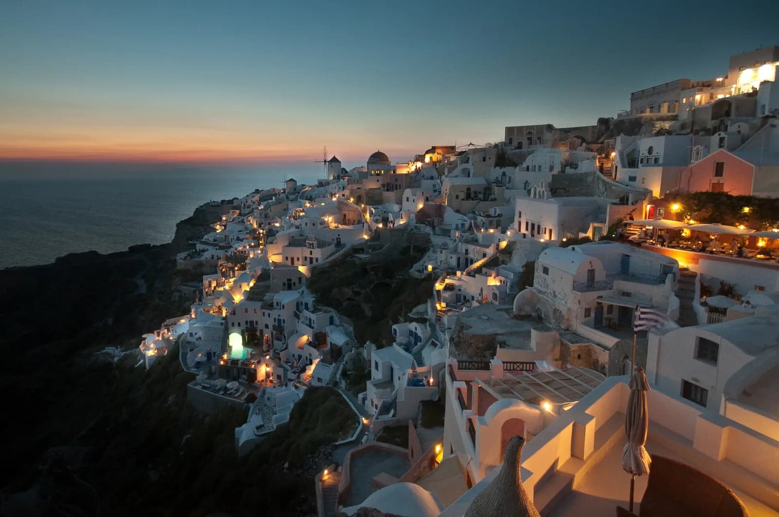 the village of Oia lighting up at dusk above the Santorini caldera