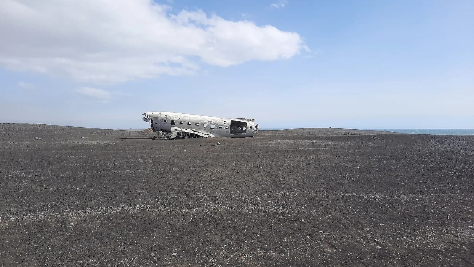 la silhouette de l'avion abandonné qui apparaît au loin dans l'immensité de sable noir