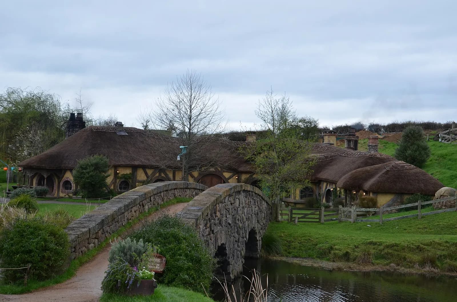 le pont en pierre mène à l'auberge du Dragon Vert au toit de chaume à Hobbiton