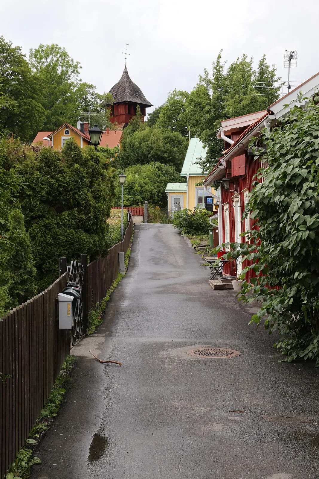 ruelle pentue bordée de maisons en bois rouge et de verdure à Sigtuna