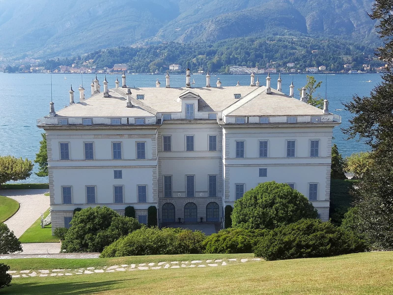 la façade néoclassique blanche de la Villa Melzi entourée de massifs, au bord du lac
