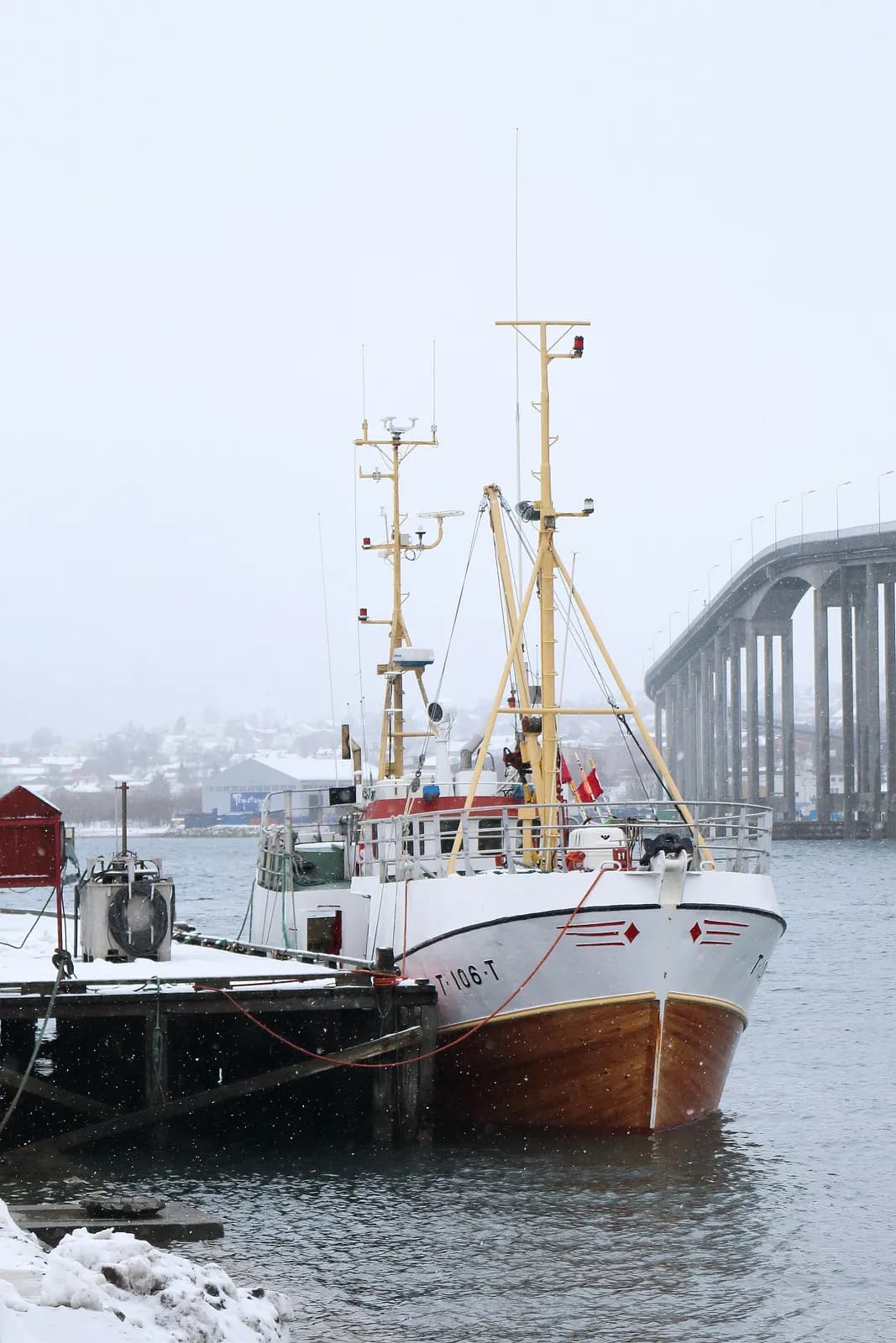 chalutier amarré au port de Tromsø sous la neige, près du pont