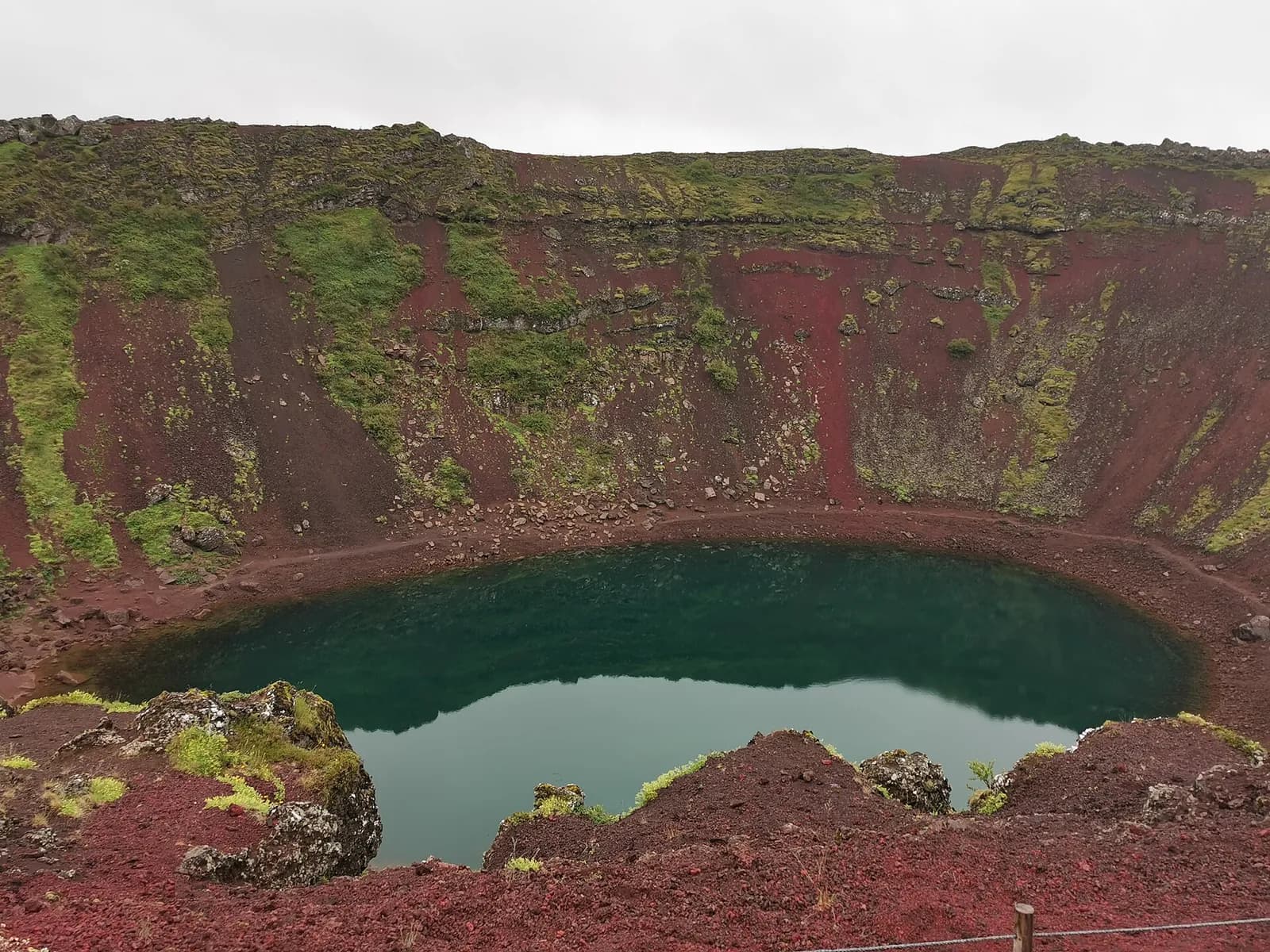 le lac vert émeraude du cratère de Kerið entouré de roches volcaniques rouges