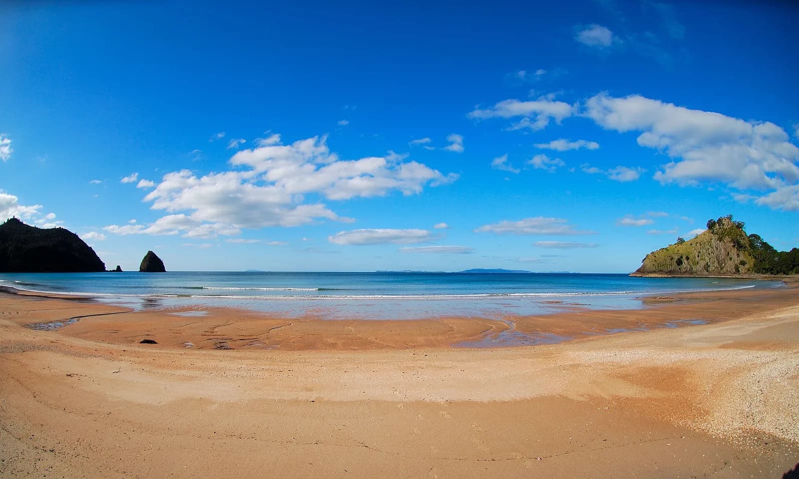 le sable doré et les rochers de New Chums Beach sous un ciel bleu à Coromandel