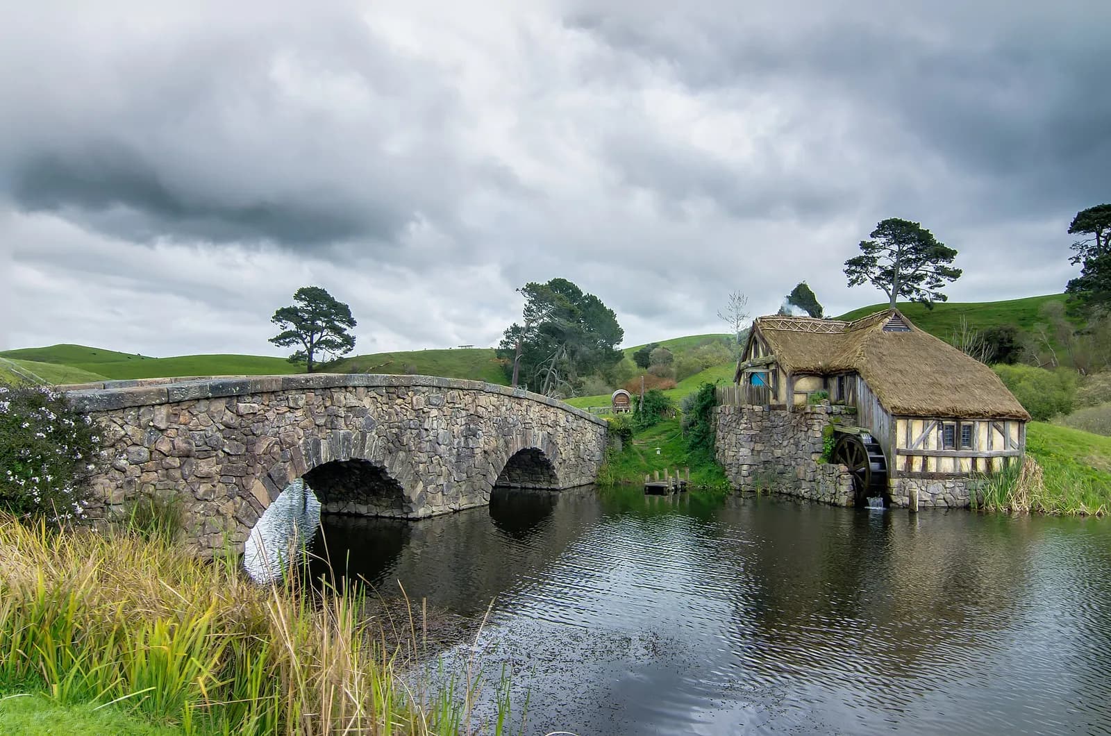 le moulin à eau au toit de chaume et le pont à double arche de Hobbiton