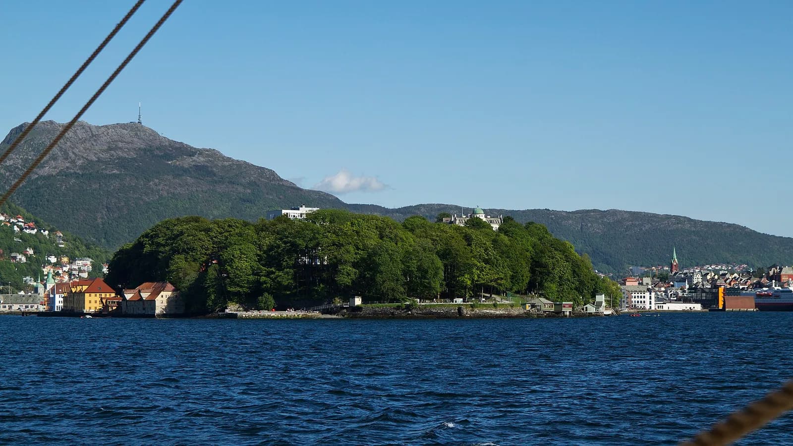 la pointe boisée de Nordnes vue depuis la mer, avec le mont Ulriken en arrière-plan