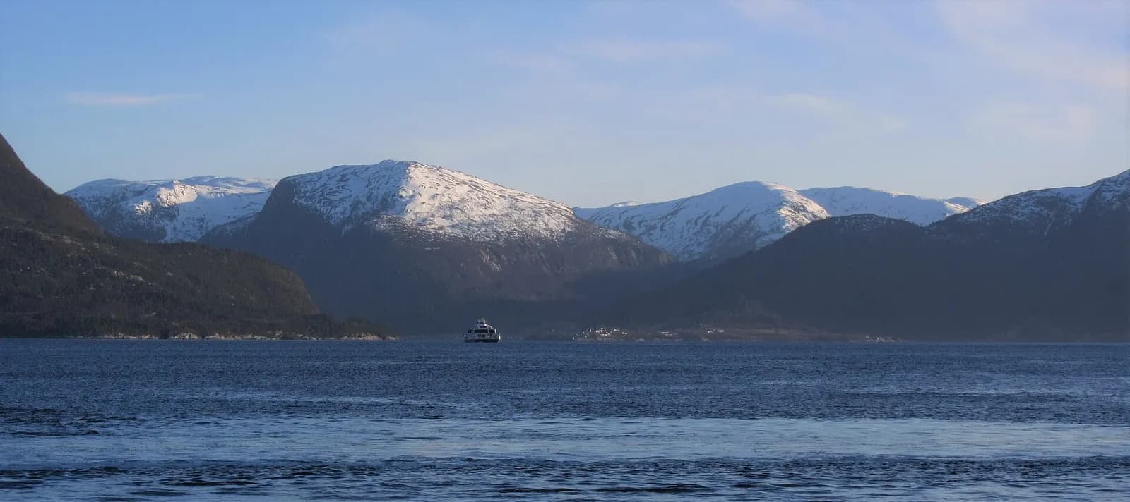 ferry traversant le Sognefjord en fin d'hiver, devant des montagnes enneigées