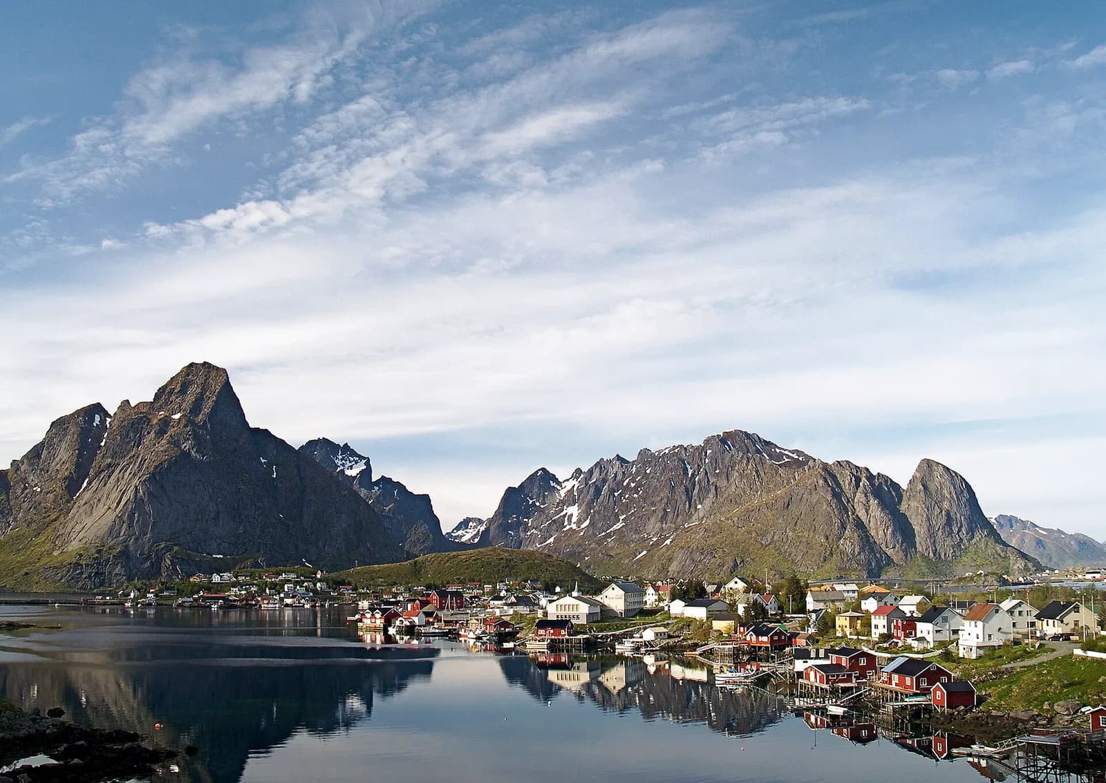 le village de Reine et ses montagnes acérées se reflétant dans l'eau calme des Lofoten