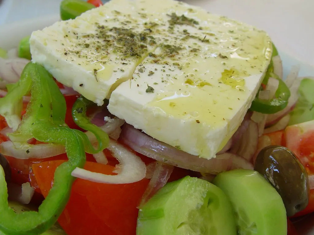 Greek salad with green pepper, olives and feta drizzled with olive oil