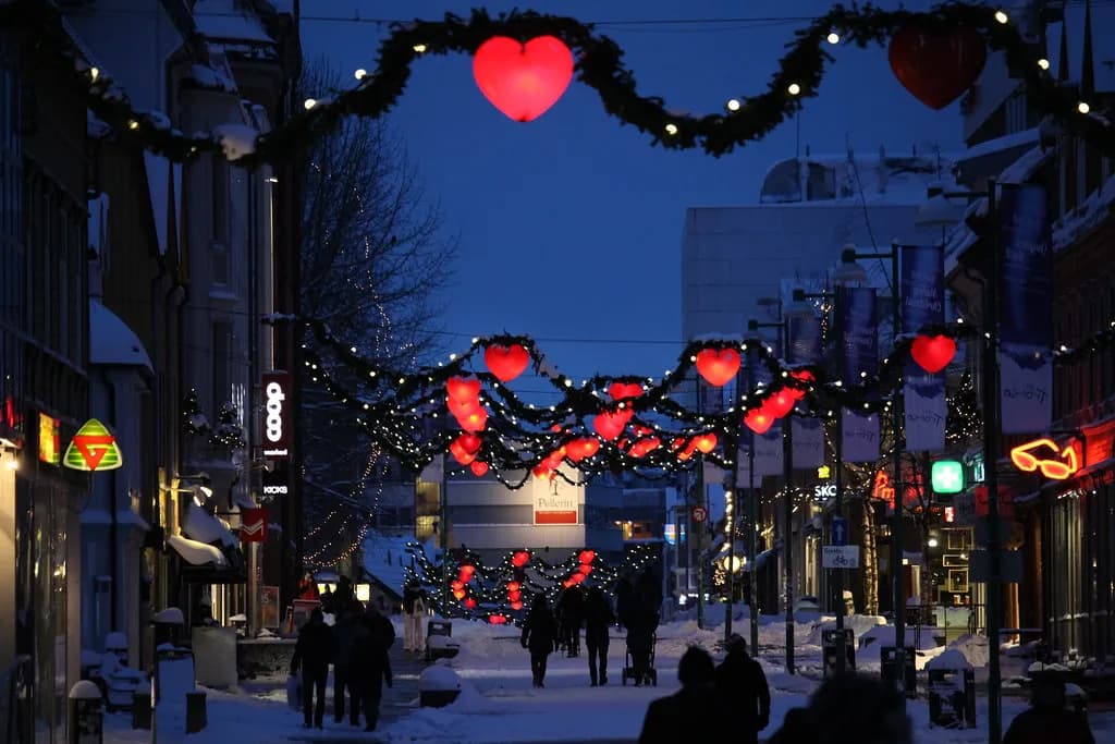 passants dans une rue piétonne de Tromsø décorée de guirlandes et de cœurs rouges