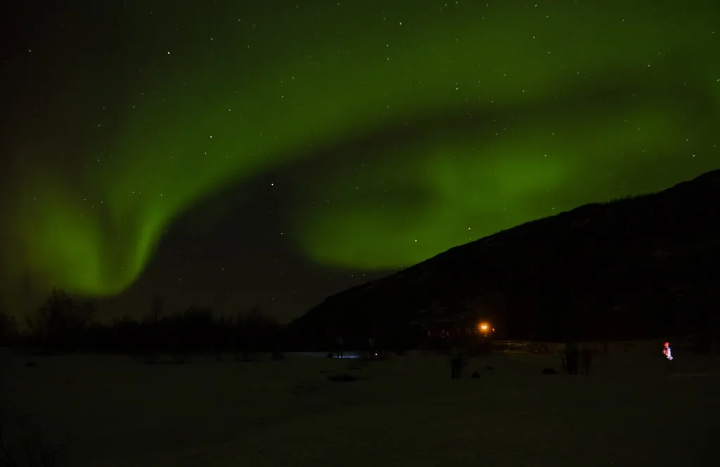 aurore boréale verte au-dessus d'une plaine enneigée du Skulsfjord, loin des lumières de la ville